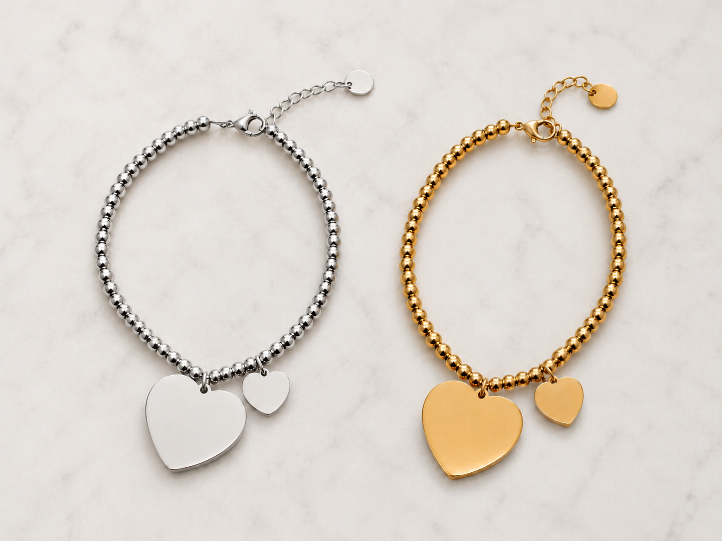 Due bracciali, uno argentato e uno dorato, con ciondoli a cuore